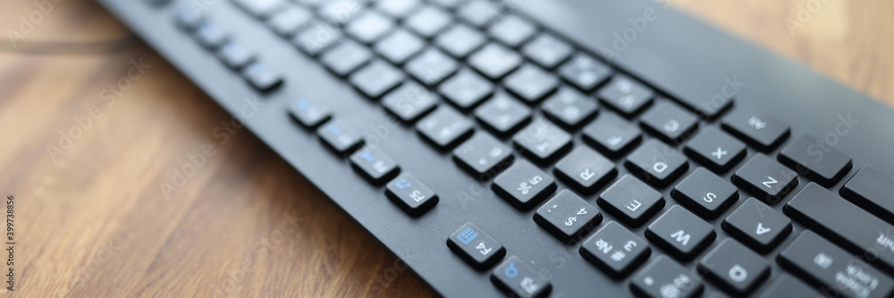 Black keyboard lying on wooden table in office closeup. Repair and sale of computer equipment concept Black keyboard lying on wooden table in office closeup. Repair and sale of computer equipment concept
