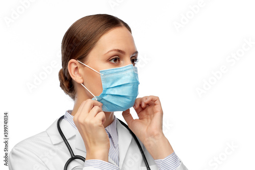 medicine, profession and healthcare concept - female doctor in white coat with stethoscope wearing medical mask