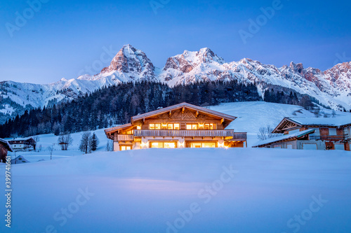 Wooden chalet in the alps on a cold winter evening photo