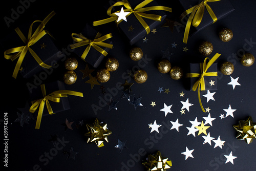 Black gifts with gold ribbons and gold christmas balls and stars.Set of gift box isolated on black background.Christmas gift boxes on black background.Merry Christmas and Happy Holidays greeting card.