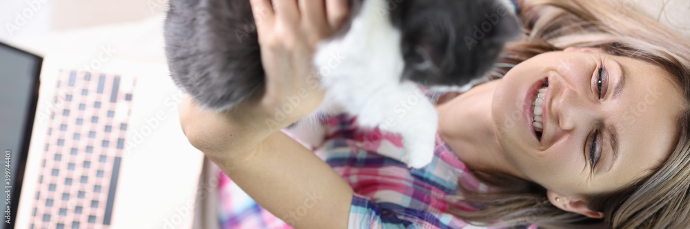 Smiling woman is sitting on the couch and holding cat. Pets Stress Relief Concept Smiling woman is sitting on the couch and holding cat. Pets Stress Relief Concept