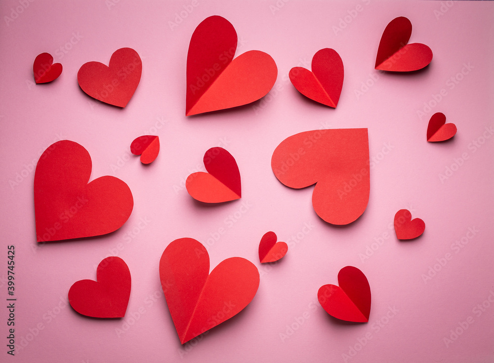 Red hearts cut from paper on pink background, paper craft origami style, from above. Romantic Valentine's day background and love concept. Different size red hearts top view, paper art design Red hearts cut from paper on pink background, paper craft origami style, from above. Romantic Valentine's day background and love concept. Different size red hearts top view, paper art design