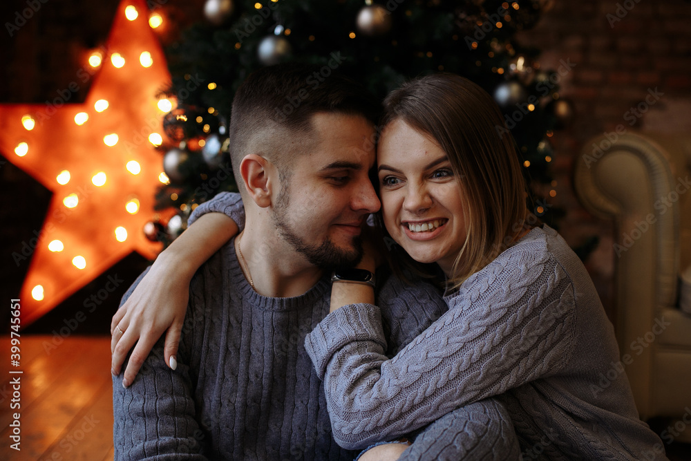 lovers are sitting under a christmas tree with gifts