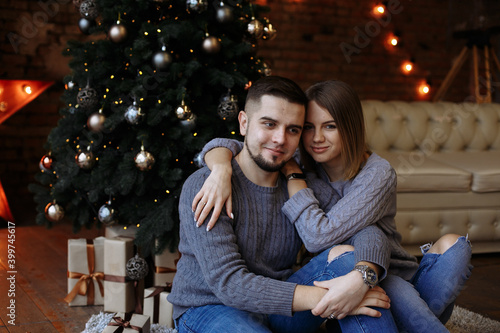lovers are sitting under a christmas tree with gifts