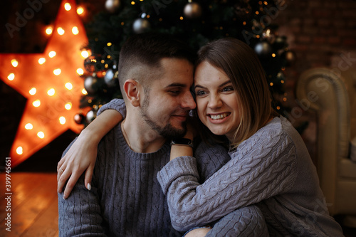 lovers are sitting under a christmas tree with gifts