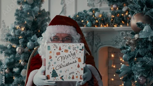 Santa gives a gift. Santa hands the gift box to the camera.