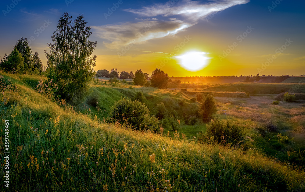 Sunset over beautiful hills with green grass and wildflowers