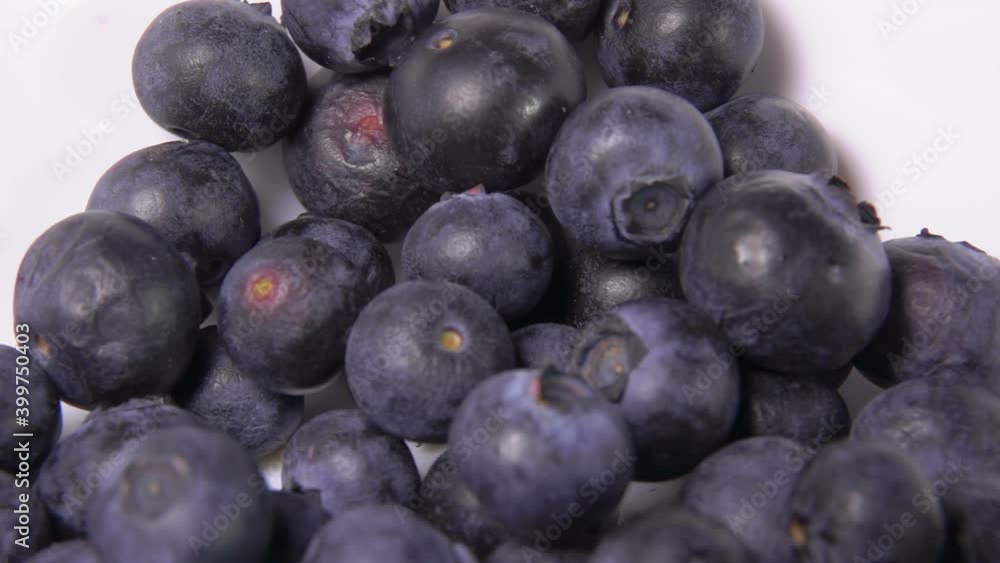 Close-up of large juicy blueberries falling into the white bowl in slow motion Close-up of large juicy blueberries falling into the white bowl in slow motion