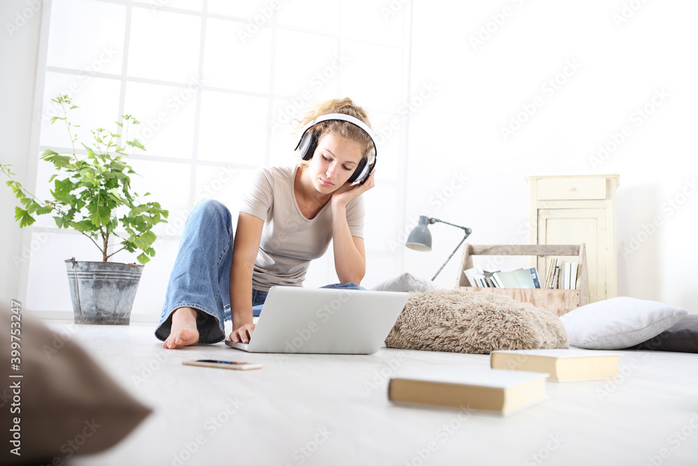 young woman sitting in living room studying with headphones and computer, stay at home concept young woman sitting in living room studying with headphones and computer, stay at home concept