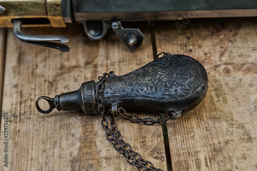 old vintage iron powder flask for charging musket closeup on wooden background