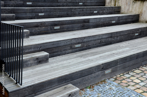 seating benches are part of a staircase which is built of dark gray planks and black metal railings. position lights are used for orientation and safety of movement photo