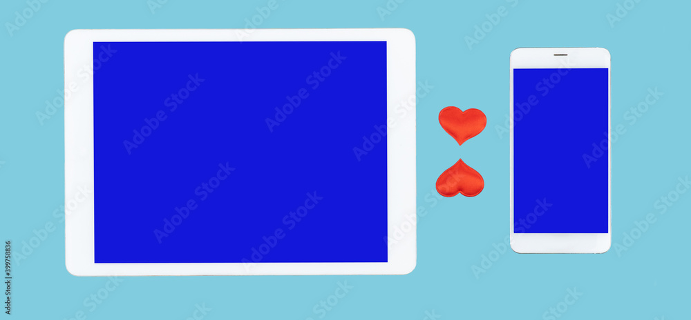 cell phone and tablet computer on blue background. red hearts between gadgets. concept of sending romantic messages. Love chat cell phone and tablet computer on blue background. red hearts between gadgets. concept of sending romantic messages. Love chat