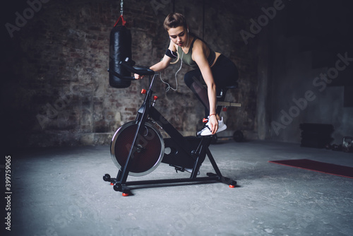 Focused sportswoman starting exercising on cycling machine