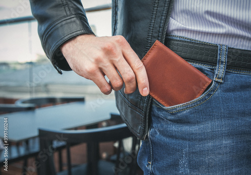 The man pulls a brown leather wallet out of his jeans pocket photo