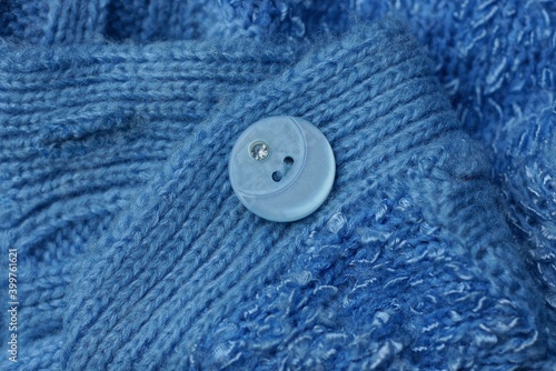 one large round plastic button on a blue woolen garment fabric