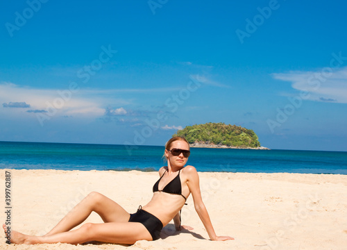Beautiful girl of twenty five years old in a black swimsuit on the beach against the background of the sea