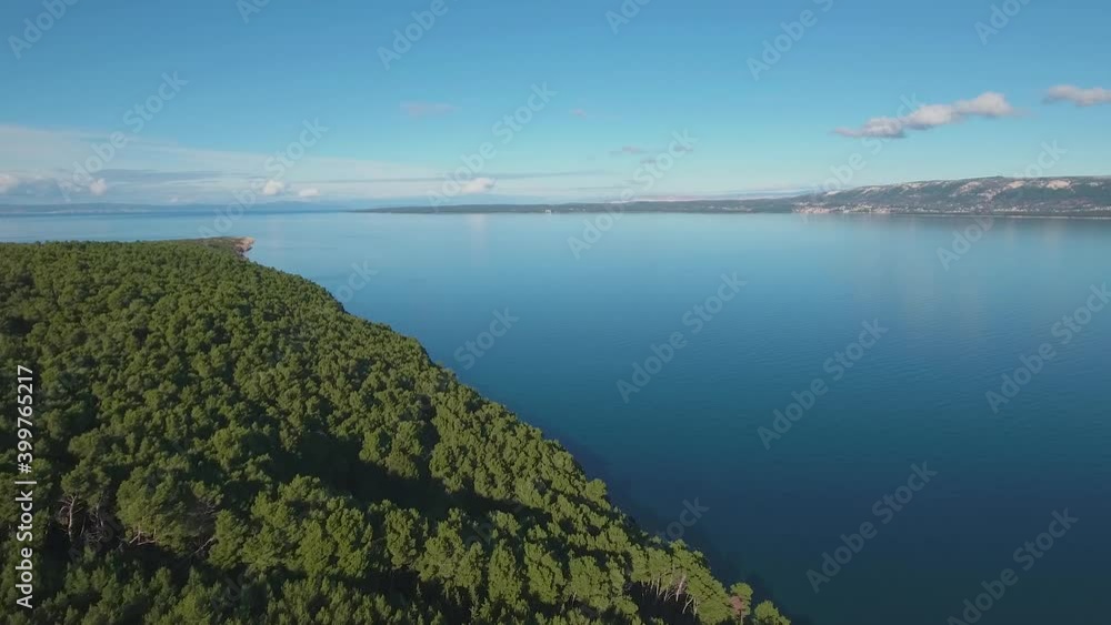 The forest with its greenery descends all the way to the sea, where the green color merges with the blue. The shot slowly glides forward, following the green seashore. The forest with its greenery descends all the way to the sea, where the green color merges with the blue. The shot slowly glides forward, following the green seashore.