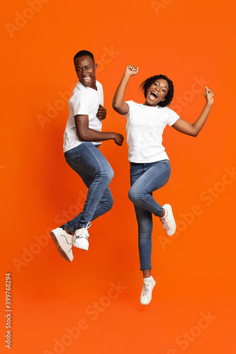 Carefree african man and woman dancing on orange