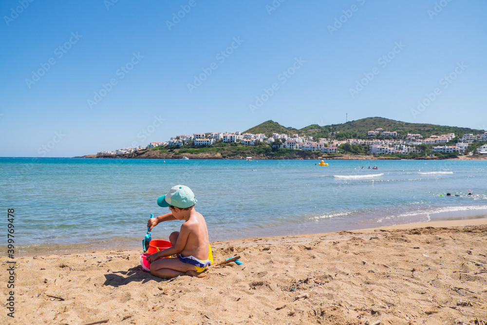 Menorca, Spain - August 6, 2020: Baby girl playing in a beach. Cala Tirant, Fornells, Menorca, Balearic Islands. Spain. Menorca, Spain - August 6, 2020: Baby girl playing in a beach. Cala Tirant, Fornells, Menorca, Balearic Islands. Spain.