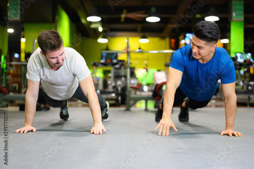 Two young men doing high planks in gym. High quality photo