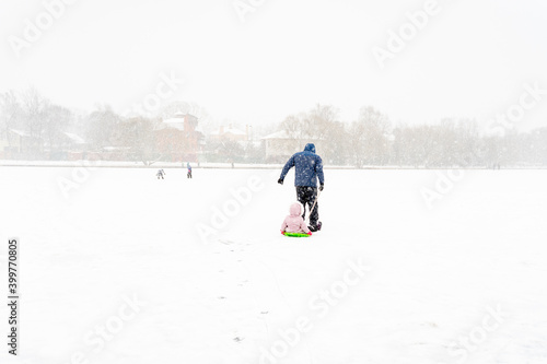 dad is driving his daughter on a sled in the snow