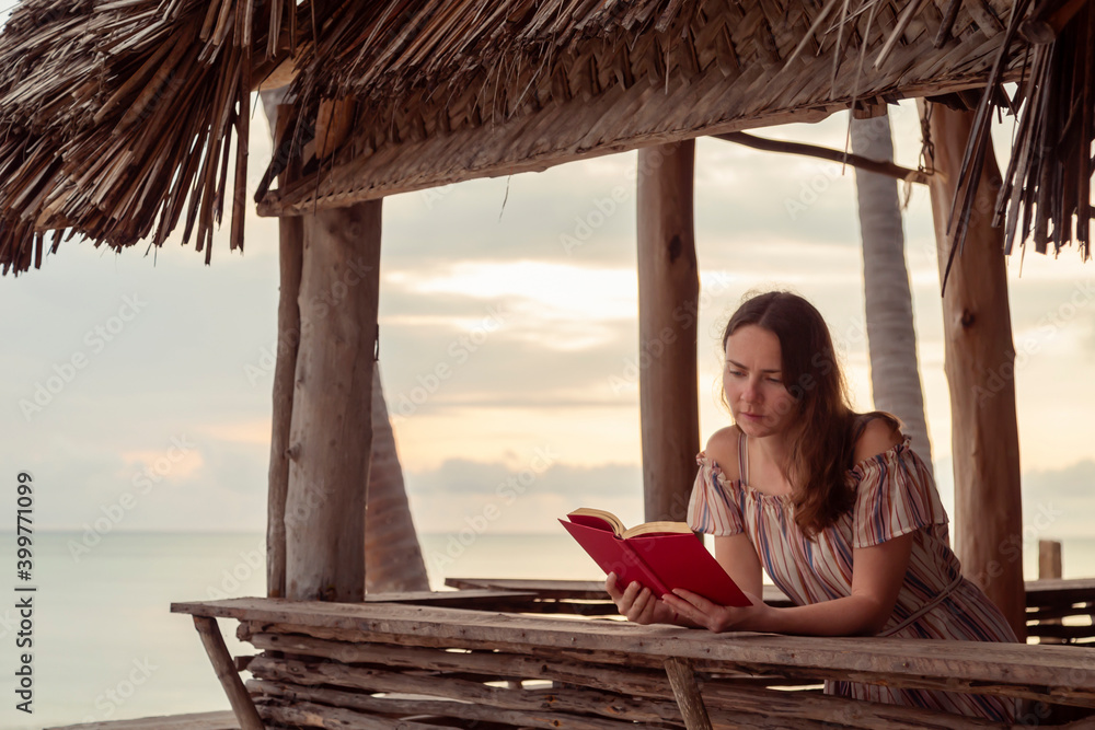 Woman reading a book at beach bar counter while on vacation