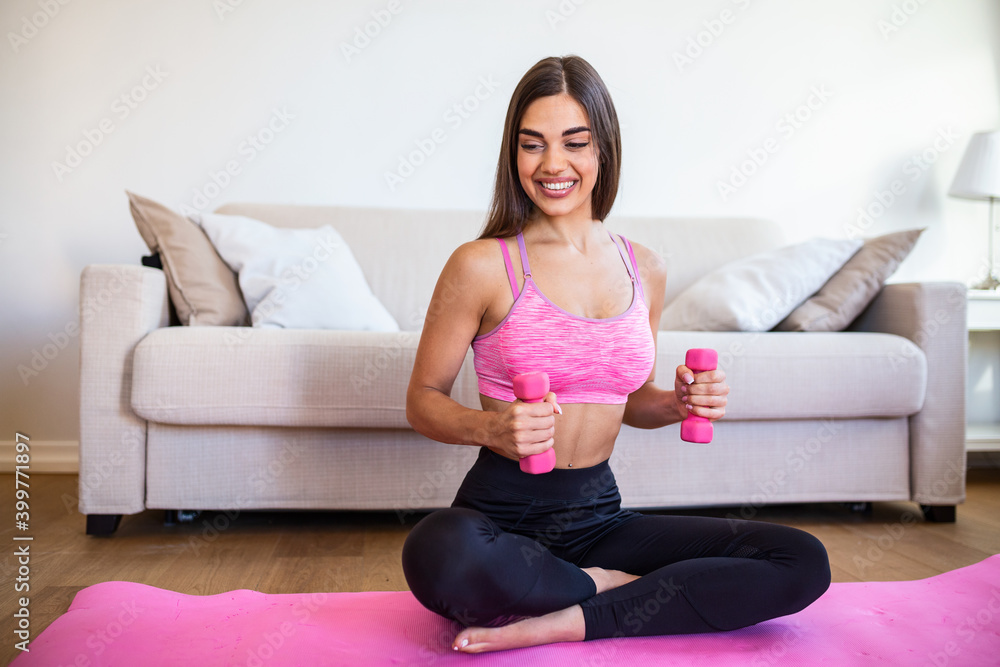 Young woman exercise with dumbbells at home and watching tutorial lesson on laptop computer. happy young female doing arm workout using dumbbells and looking at tutorial on her laptop Young woman exercise with dumbbells at home and watching tutorial lesson on laptop computer. happy young female doing arm workout using dumbbells and looking at tutorial on her laptop