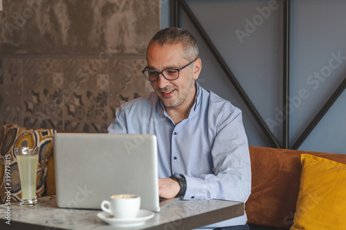 Happy businessman working on laptop in a cafe.