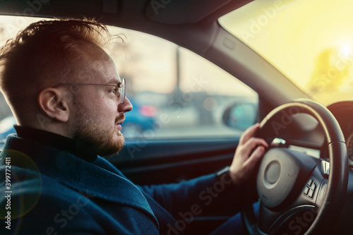 male driver in business attire drives a car in winter on a sunny day. business trip behind the wheel