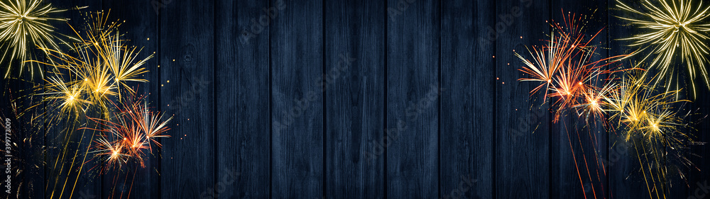Naklejka premium Silvester party New year background banner panorama long- Golden red Firework and sparklers on rustic blue wooden texture, with space for text 