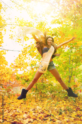 Happy young caucasian woman jumping in leaves in the autumn forest.