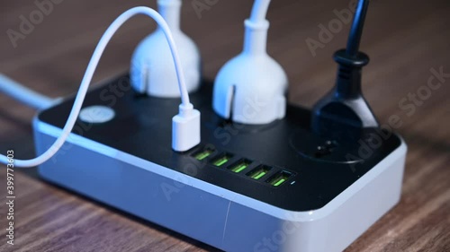 Close-up of a male hand plugging cables into a power outlet. Modern convenient multi-port usb charger for devices. 