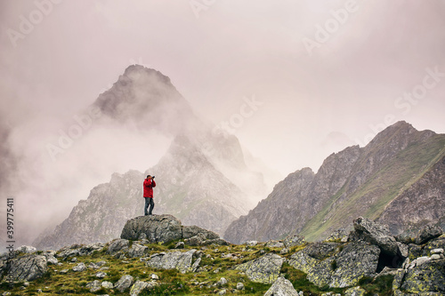 Hiker with camera standing on top of a mountain. Landscape photographer photographs a mountain view. © serkucher