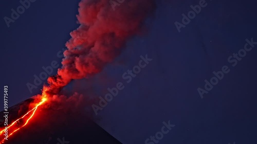 Night timelapse of Klyuchevskaya Sopka or Klyuchevskoy volcano eruption on Kamchatka. Smoke and burning lava erupting from vent. Stars moving on sky. Concept of wild nature and geology. photo