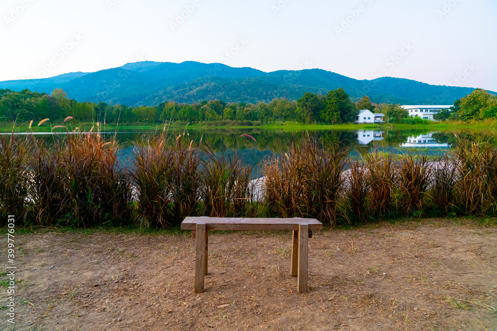 wood bench with beautiful lake at Chiang Mai with forested mountain and twilight sky
