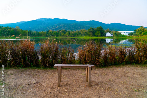 wood bench with beautiful lake at Chiang Mai with forested mountain and twilight sky