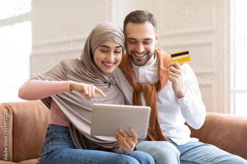 Muslim Family Using Digital Tablet Shopping Online Sitting At Home