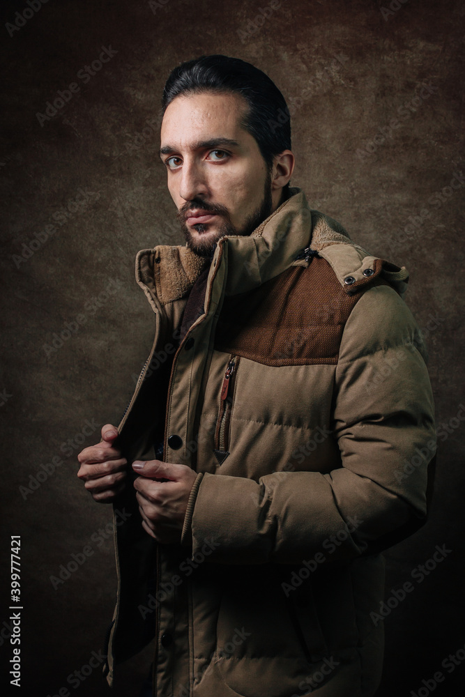 Portrait of a man. A man in a winter jacket. Winter fashion. Portrait on a brown background Portrait of a man. A man in a winter jacket. Winter fashion. Portrait on a brown background
