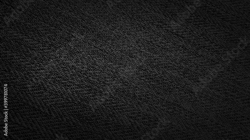 the texture of dark black herringbone pattern fabric with dark gradient from border. black knit fabric with geometric patterns of wool and cotton.