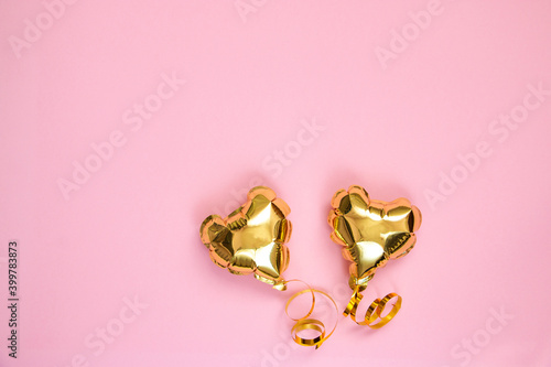 Gold balloon in the shape of a heart on a pink background. Valentine's day concept. Copy space for text.