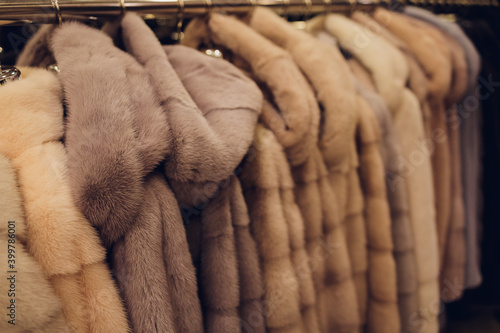 Luxury mink coats. Grey, brown, pearl color fur coats on showcase of market. Best gift for women is mink coat. Outerwear. Close up. photo