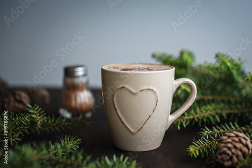 Christmas coffee with cinnamon on a wooden table. Spruce branches and cones, chocolate spoon.