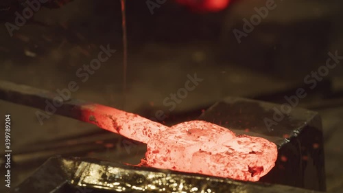 Master Swordsmith working a glowing hot ingot then back on forge to reheat.