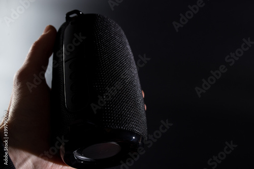 wireless speaker in hand. Portable black speaker. Speaker with copyspace.