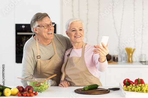Joyful Elderly Spouses Making Selfie Having Fun Cooking In Kitchen