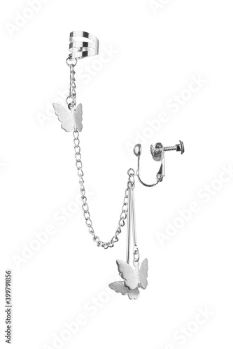 Subject shot of one silver combined earring with cuff clip fastening for unpierced lobe of ear. Cuff and clamp earring are connected with chains with dangling silver butterflies. photo