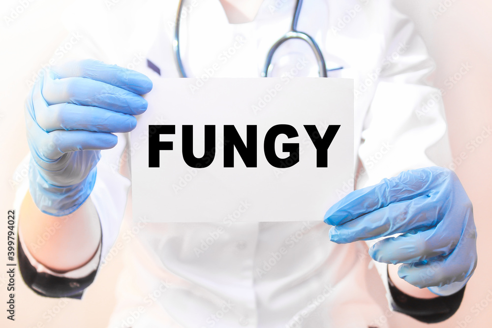 The doctor's blue - gloved hands show the word FUNGY - . a gloved hand on a white background. Medical concept. the medicine The doctor's blue - gloved hands show the word FUNGY - . a gloved hand on a white background. Medical concept. the medicine