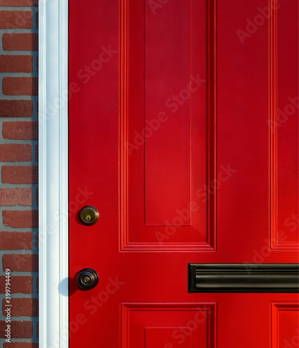 Bright red paneled front door detail with knob, lock and mail slot