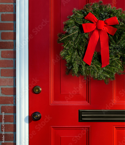 Christmas wreath on red paneled door with knob, lock and mail slot