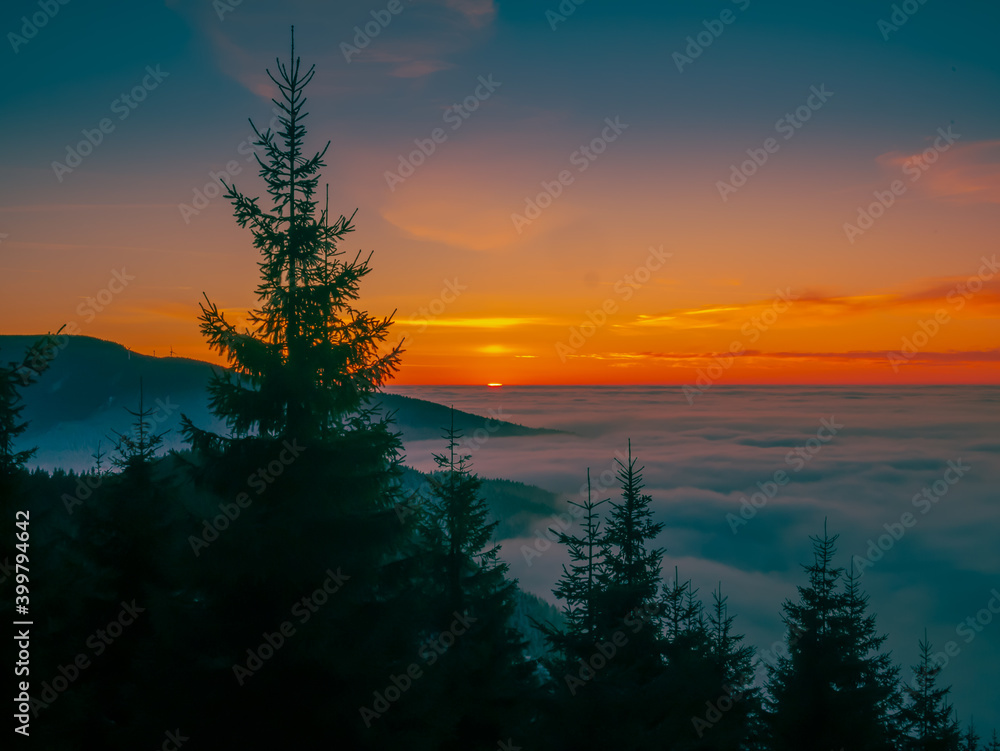 View from mountain range to the valley above fog and clouds at sunset